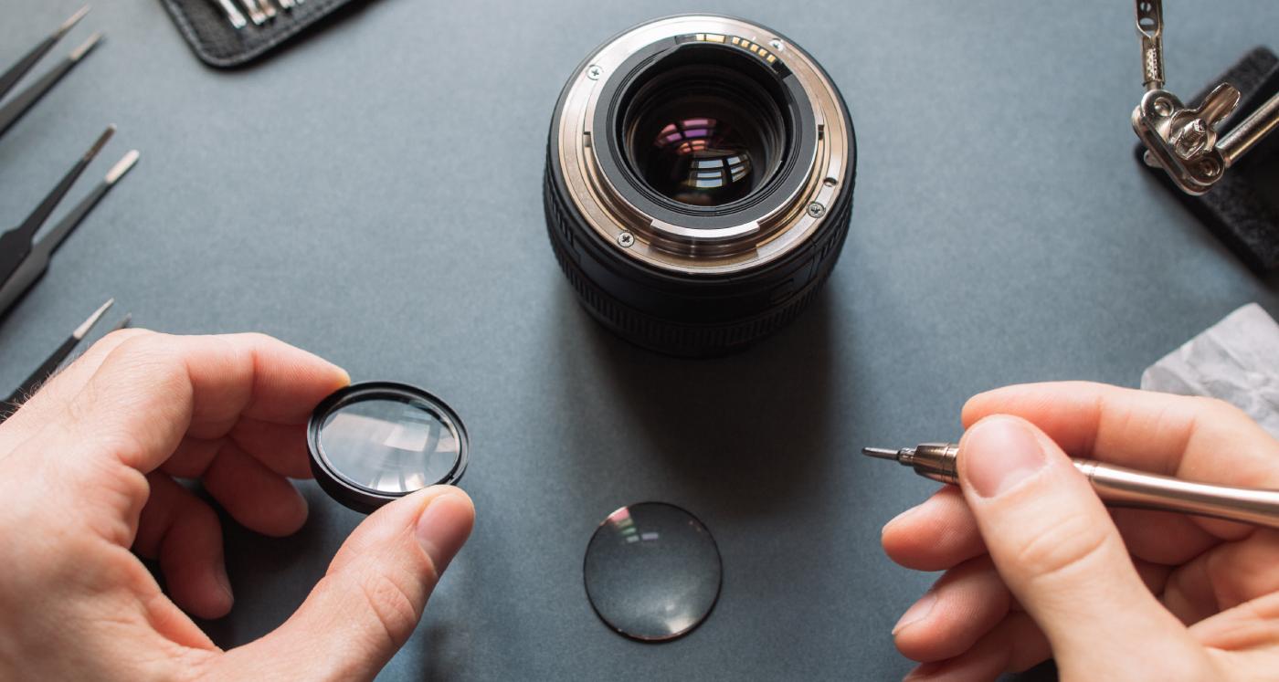 Hands holding tools ready to repair a camera lens